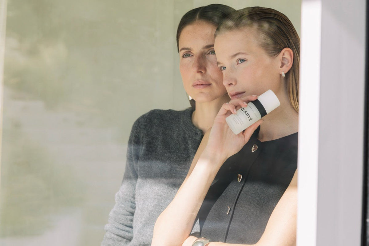 Deux femmes à une fenêtre, l'une tenant un soin Clarté Laboratoire, boutique Shopify réalisée par Stellar